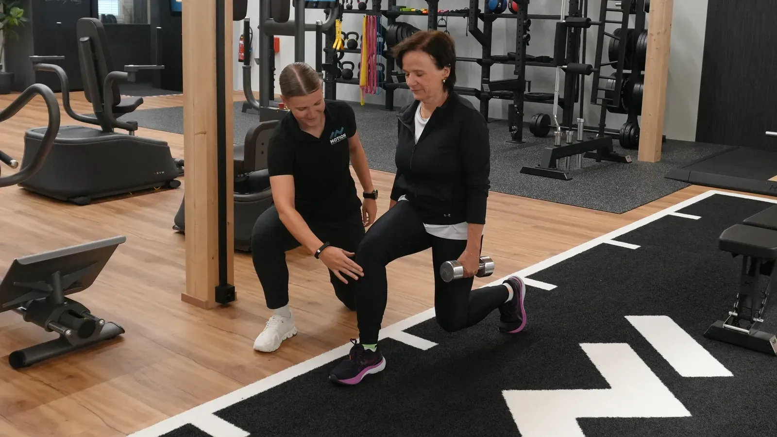 Physiotherapeutin von IN MOTION korrigiert die Übung einer Kundin auf der Trainingsfläche